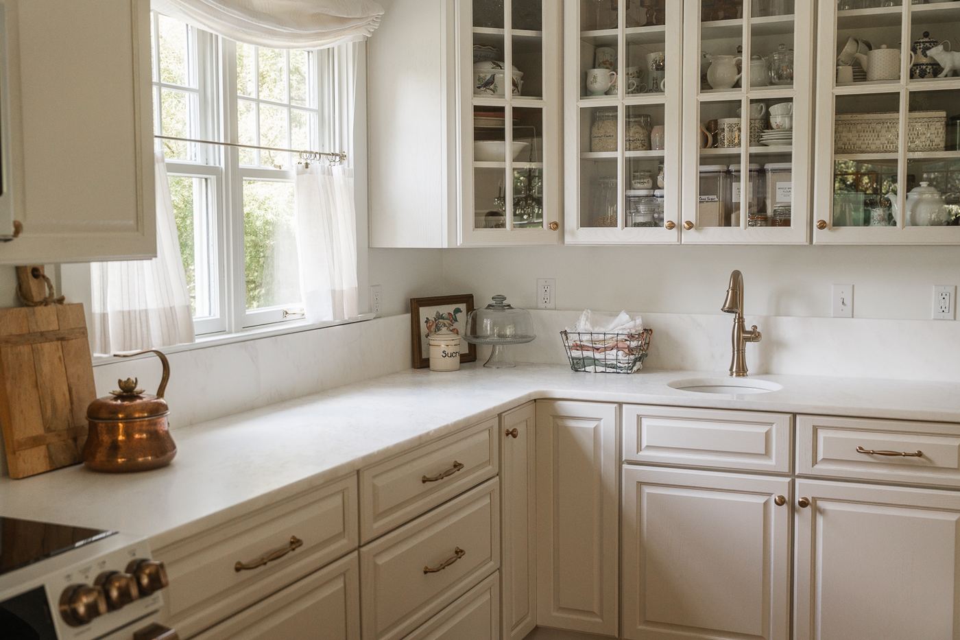 Corner marble counters with glass-front cabinets and brass hardware