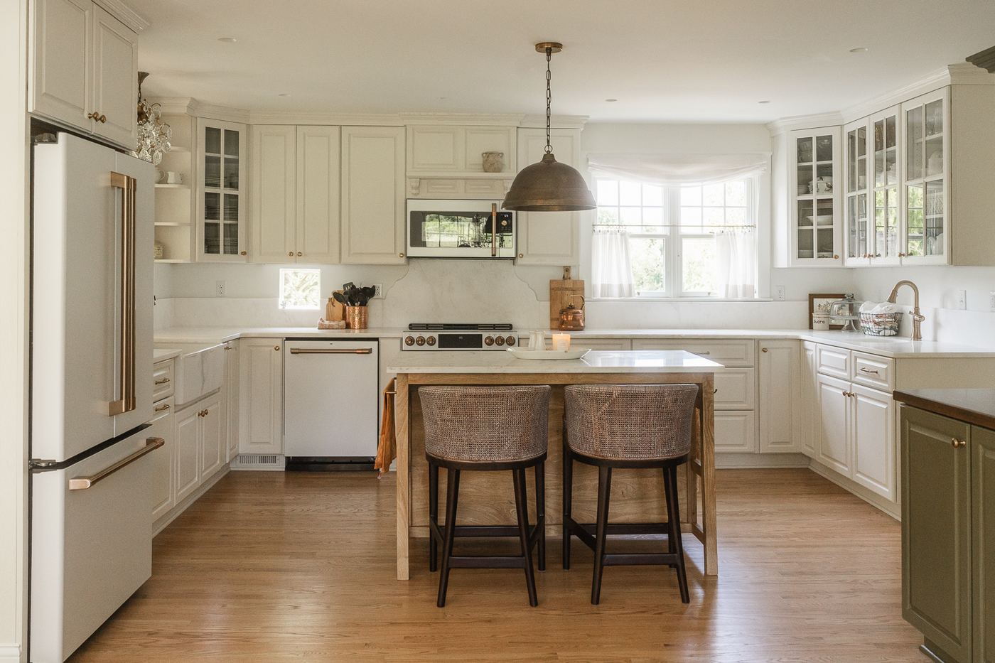 White kitchen with island, woven stools, and marble counters throughout