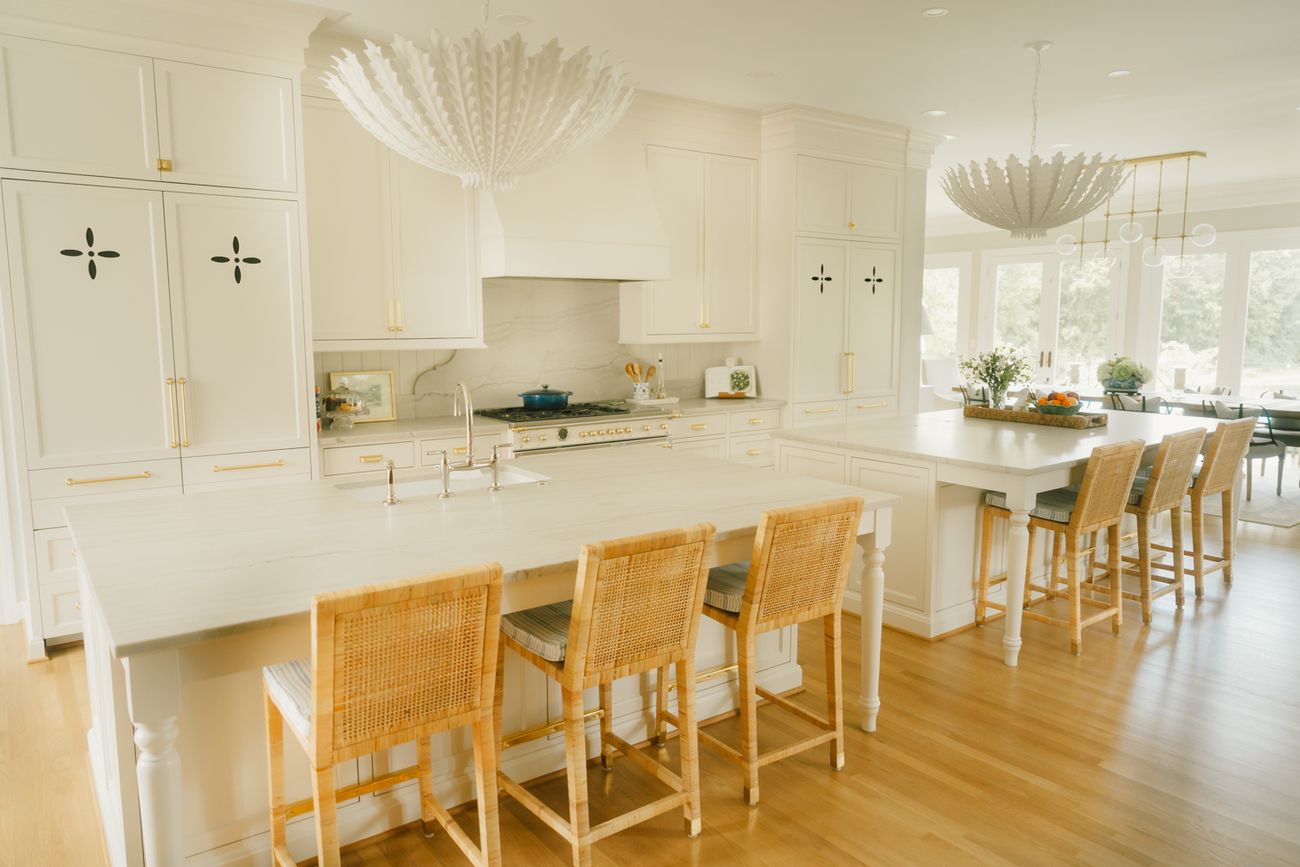 White kitchen with a long island and woven counter stools