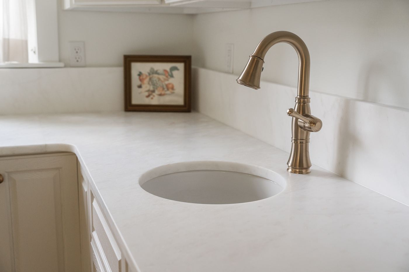 Close-up of marble countertop with round sink and brass pull-down faucet
